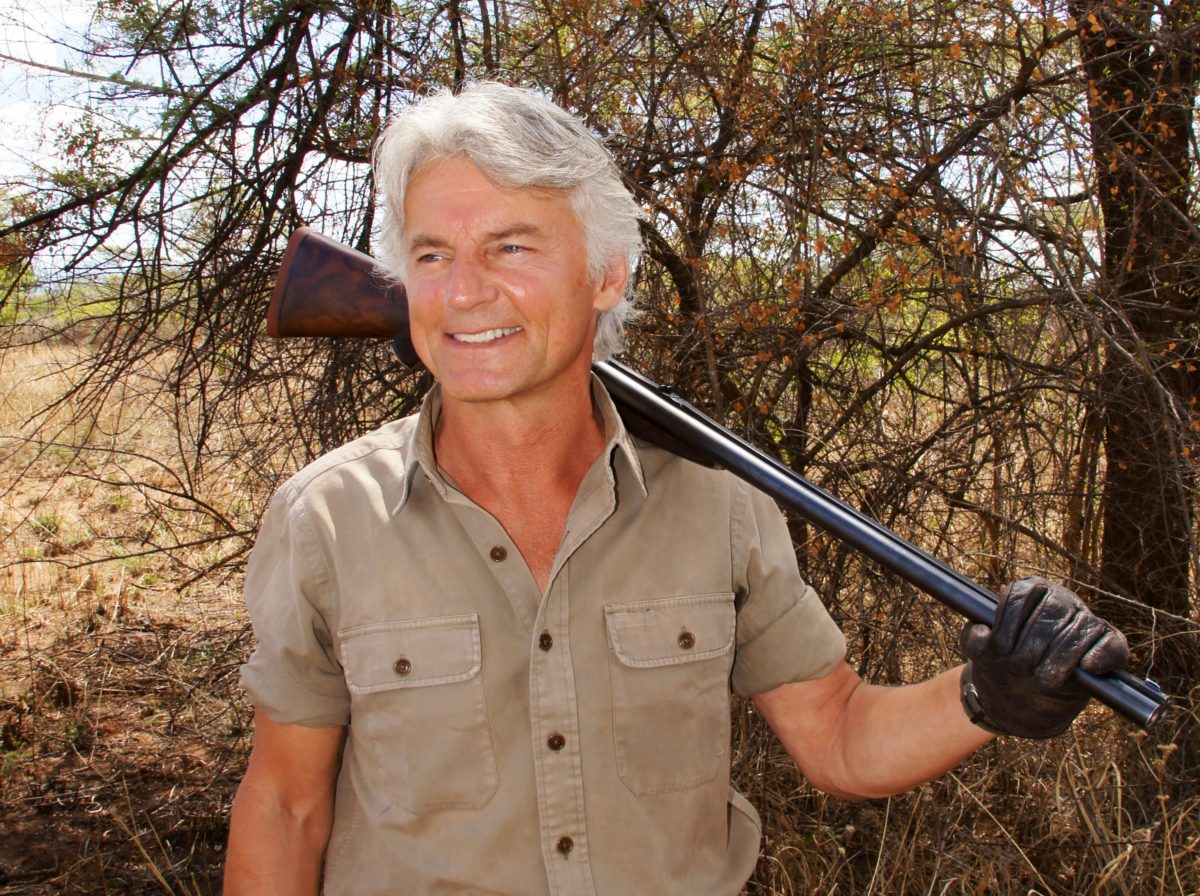 J. Alain Smith smiling with shotgun resting on shoulder